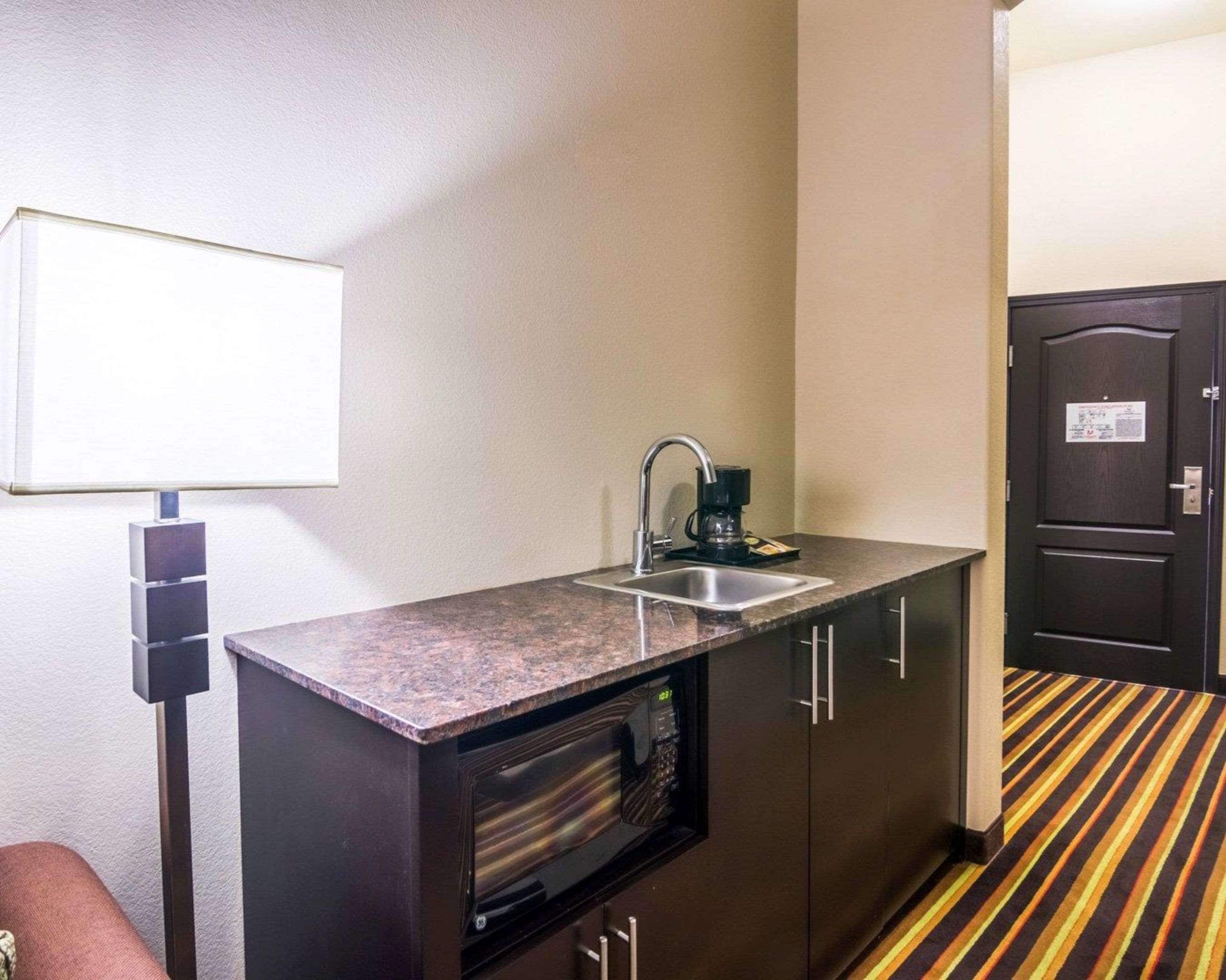 A compact kitchenette with a built-in microwave, a coffee maker, and a sink.
