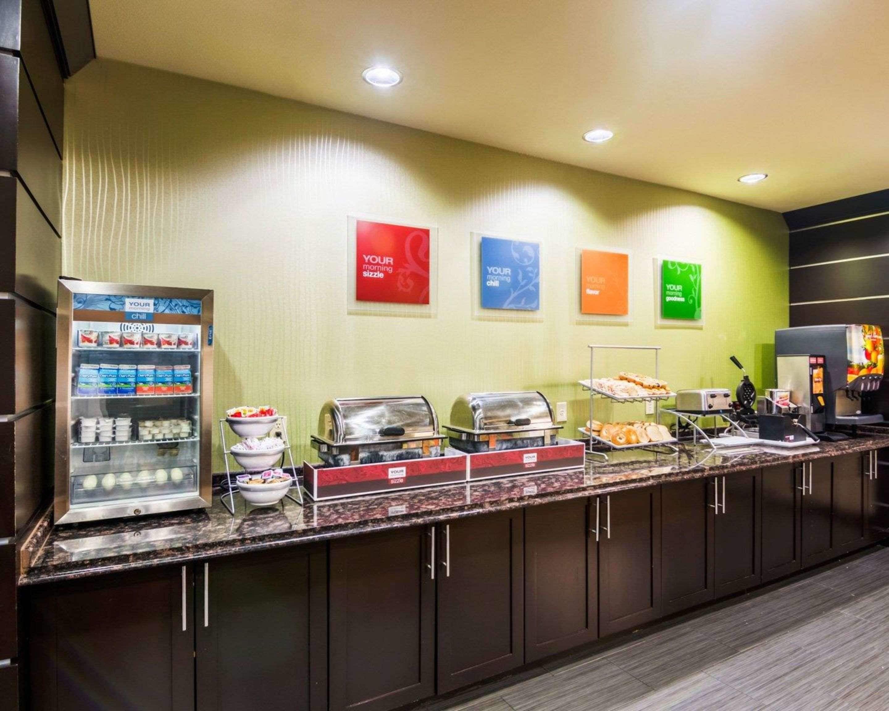 Una mesa de desayuno tipo buffet con diversos alimentos y un dispensador de bebidas.