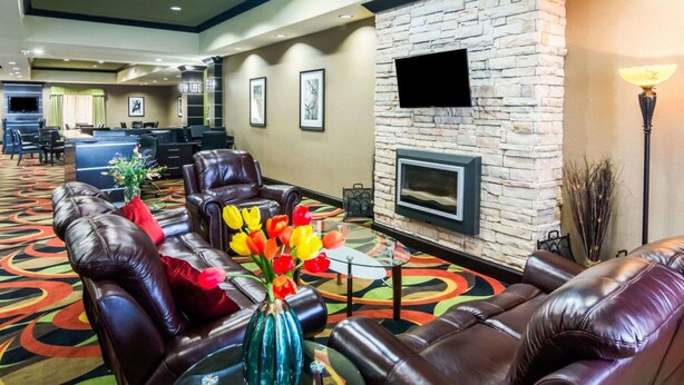 Un vestíbulo de hotel con sofás de cuero, una chimenea de piedra y un televisor montado en la pared.