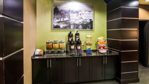 Una barra de desayuno con dispensadores de café, cuencos de fruta y recipientes de cereales.