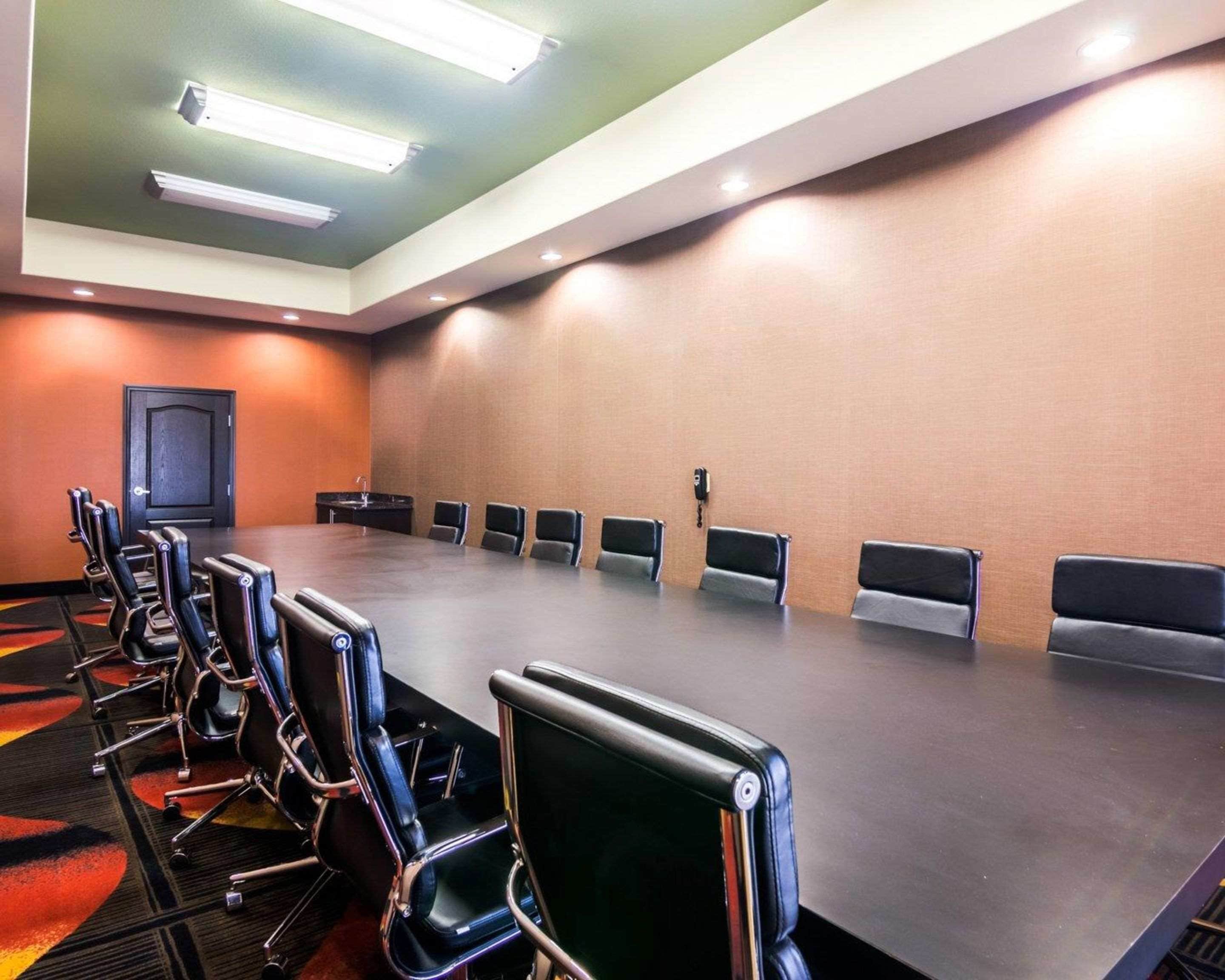 A conference room with a long table, multiple chairs, and a door.