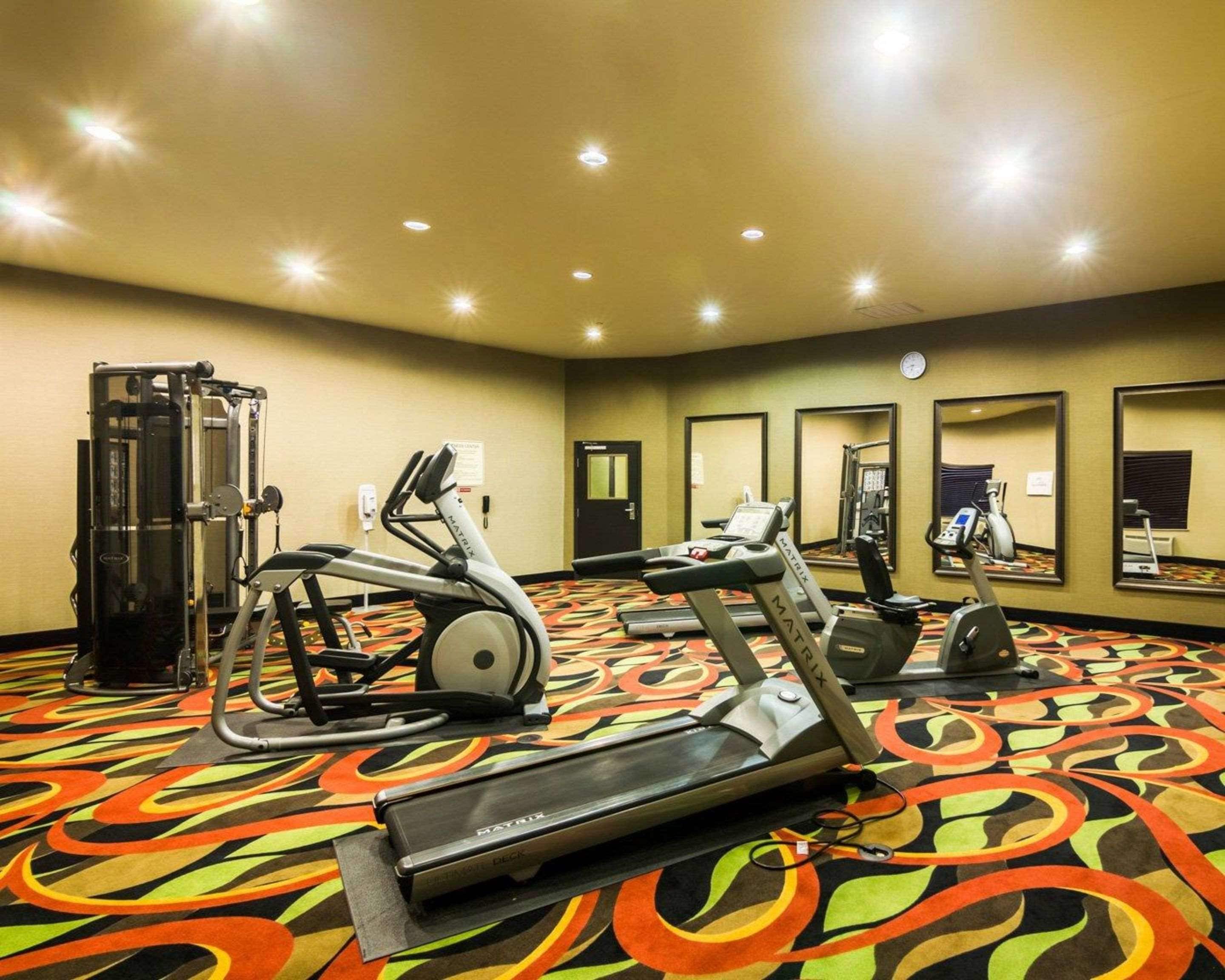 Academia de hotel com equipamentos de cardio, aparelhos de musculação e espelhos nas paredes.