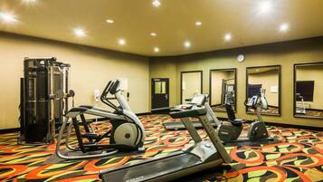 Academia de hotel com equipamentos de cardio, aparelhos de musculação e espelhos nas paredes.