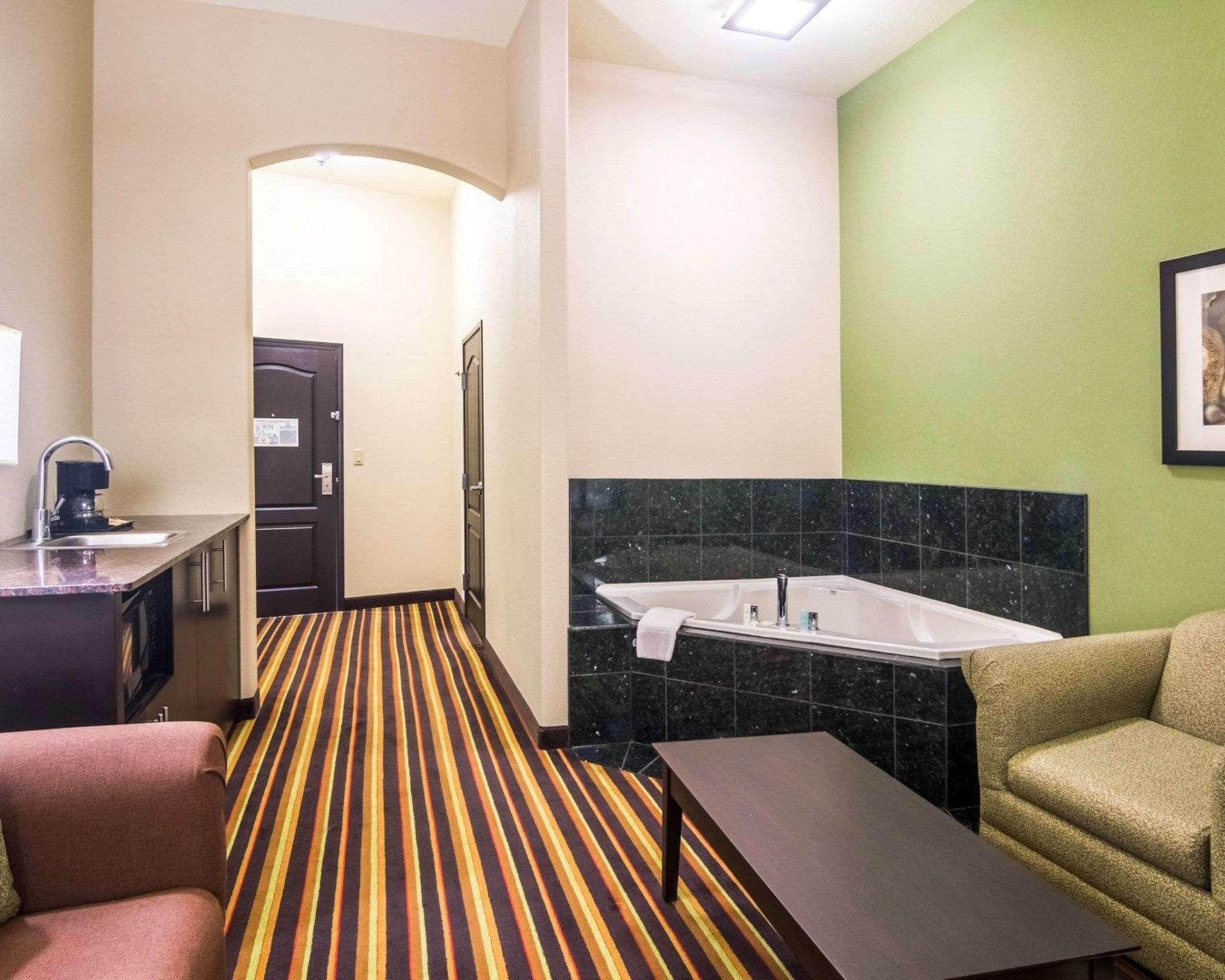 A hotel room with a striped carpet, a sink, a sofa, and a small table.
