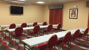 A conference room with multiple tables and chairs, a flat-screen TV, an air conditioning unit, a framed picture on the wall, and a patterned carpet. - Holiday Inn Express Bradford by IHG (Bradford)
