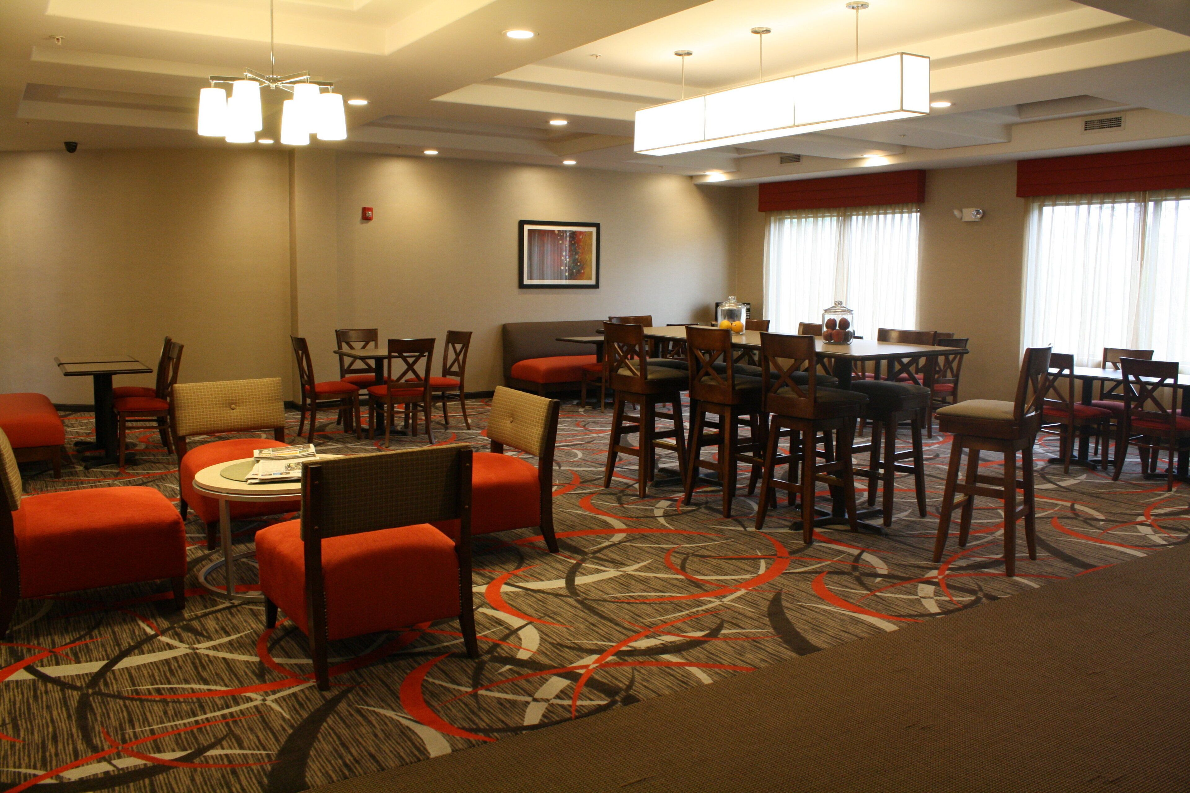 A hotel room with a dining area, multiple seating options, and a patterned carpet.