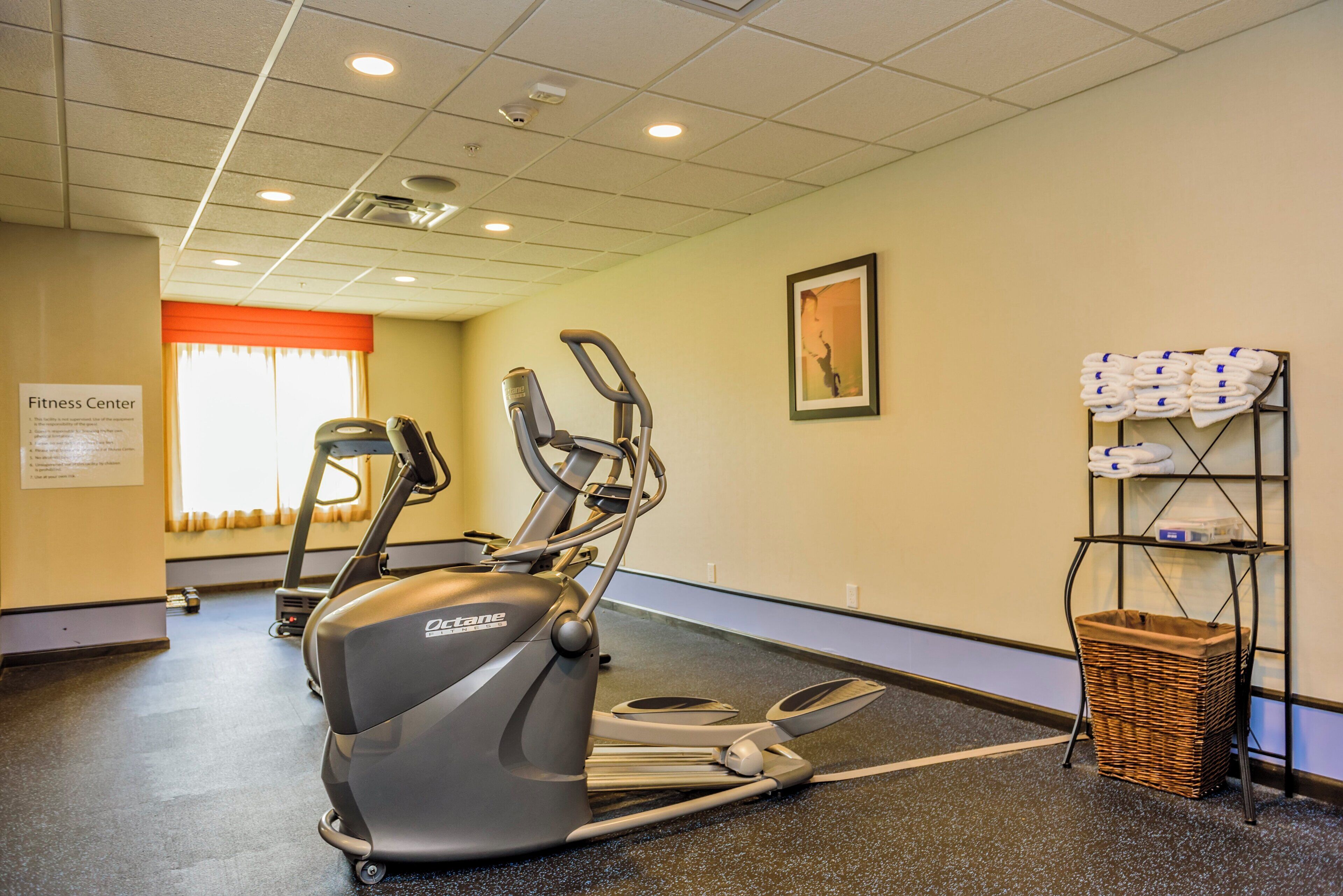 A fitness center with treadmills, an elliptical, and a wall-mounted rack with towels.