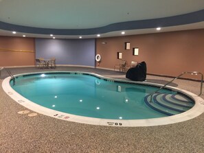 An indoor swimming pool with a depth of 3 meters, surrounded by a tiled floor and walls, with chairs and a lifebuoy against the wall.