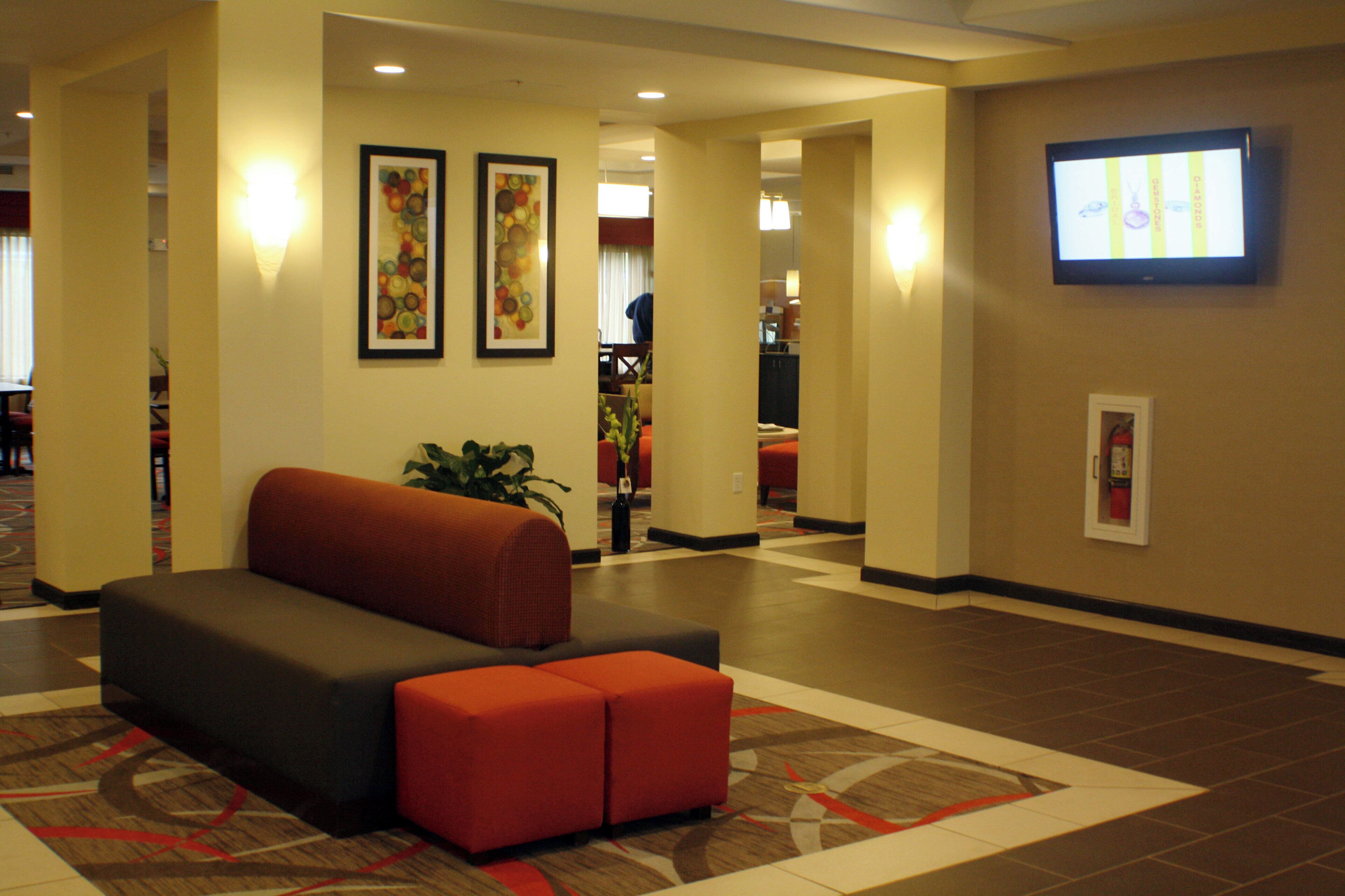 A lobby with a sofa, a television, and framed artwork on the walls.