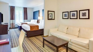 Habitación de hotel con dos camas, un sofá, una mesa de centro, televisión y cuadros en la pared.