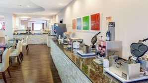 Un vestíbulo de hotel con un mostrador de recepción de mármol, una máquina de café y un fabricante de gofres.