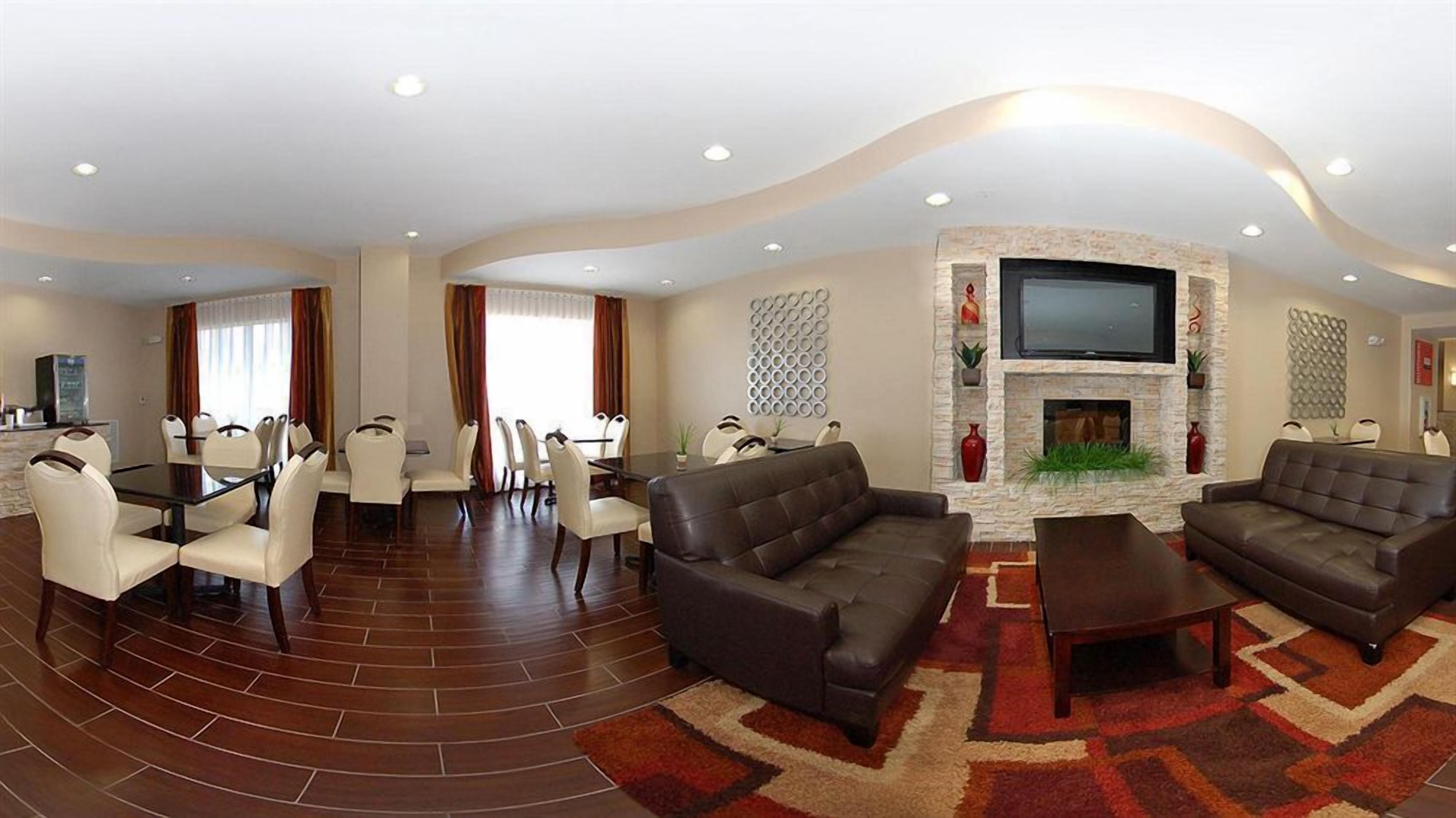 A spacious living area with a fireplace, leather sofas, and a dining area with white chairs.
