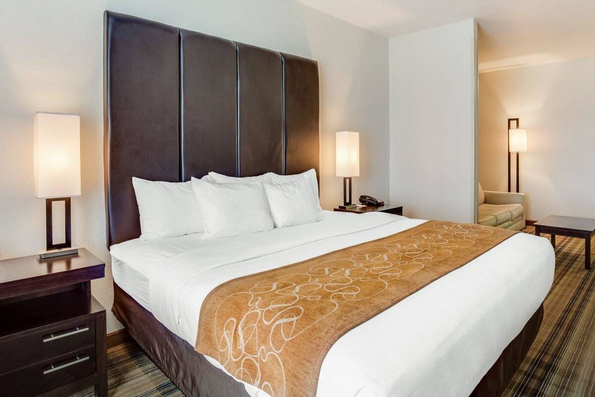A hotel room with a large bed, two bedside tables, a nightstand, a chair, and a lamp.