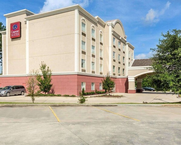 Un hôtel Comfort Suites avec une façade beige, une partie inférieure rouge et un parking situé devant l’établissement.