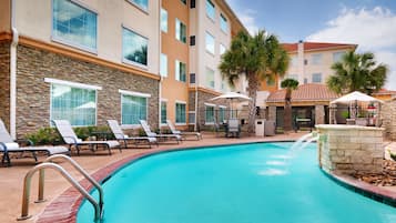Una piscina al aire libre, sillones reclinables de piscina