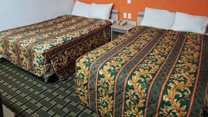 A hotel room with two beds, each with a patterned bedspread, a small bedside table with a phone, and a wall socket. - Nights Stay Hotel (Tulsa)