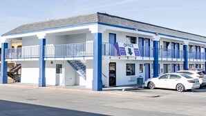 A motel with a two-story structure, a covered parking area, and a staircase leading to the entrance. - Nights Stay Hotel (Tulsa)