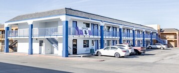 Un motel de dos pisos, con estacionamiento techado y una escalera que lleva a la entrada.