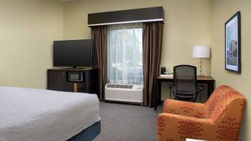 Une chambre d’hôtel avec un lit, un bureau avec un ordinateur, une télévision et une chaise.