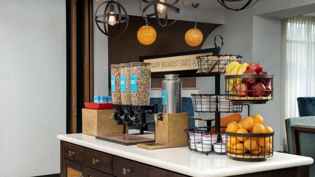 A breakfast bar with various fruits, a coffee machine, and a sign that reads "HAPPY BREAKFAST STARTS HERE". - Hampton Inn Knoxville/Clinton I-75 (Clinton)