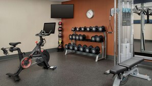 A gym with exercise equipment, a wall-mounted clock, and a television. - Hampton Inn Knoxville/Clinton I-75 (Clinton)