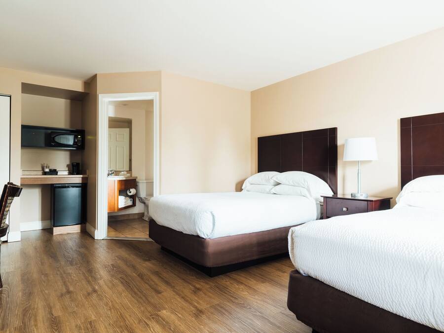 Une chambre d’hôtel avec deux lits, un four à micro-ondes, une petite kitchenette et un plancher en bois.