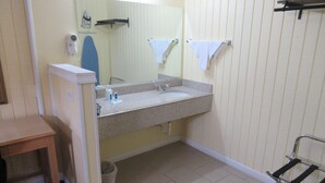 Ein Badezimmer mit Waschbecken, Spiegel, Handtuchhalter und einem kleinen Tisch.