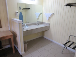 A bathroom with a sink, mirror, towel rack, and a small table.
