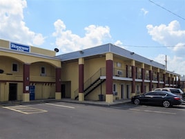 A motel with a sign reading "Rodeway Inn" and a parking lot with cars.