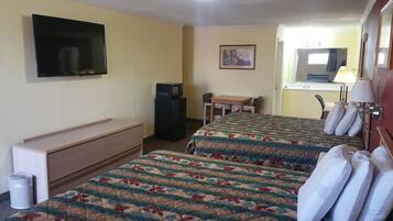 Una camera d'albergo con due letti, una televisione, una scrivania, una sedia, un cestino e un quadro appeso al muro.