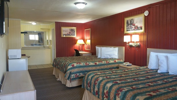 Ein Hotelzimmer mit zwei Betten, einem Schreibtisch, einem Stuhl, einem kleinen Kühlschrank und einem sichtbaren Badezimmer hinter einer geöffneten Tür.