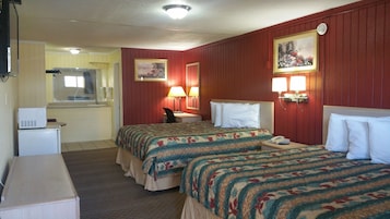 A hotel room with two beds, a desk, a chair, a small refrigerator, and a bathroom visible through an open door.