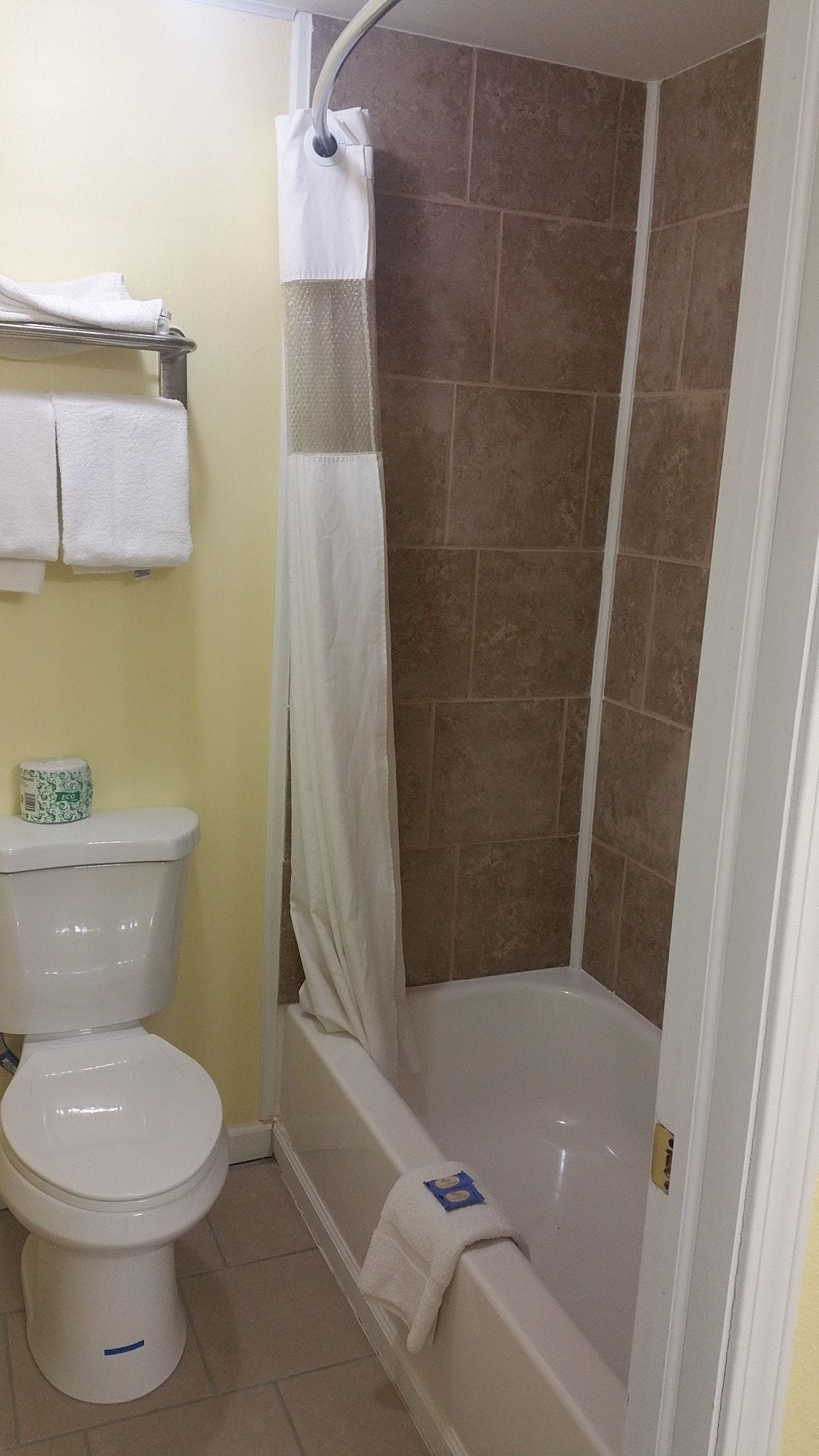 A bathroom with a toilet, a shower with a curtain, and a bathtub.