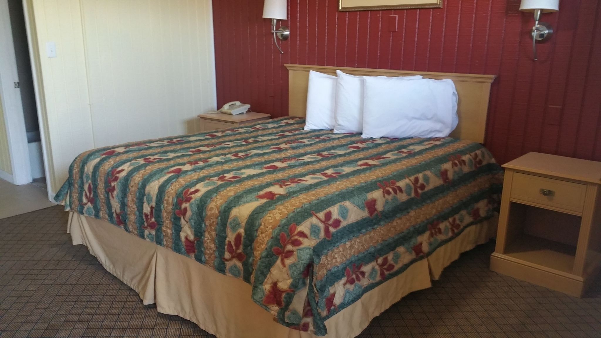 Ein Hotelzimmer mit Bett, Nachttisch mit Lampe und Ablagefläche.