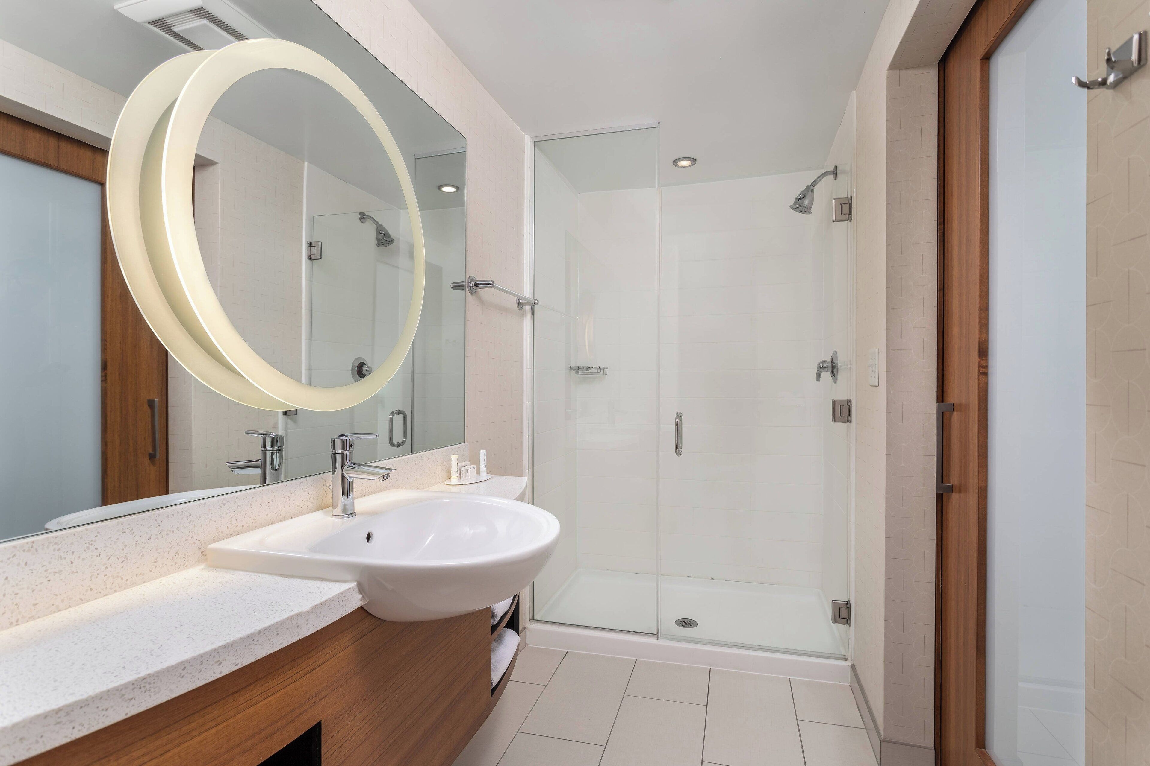 Une salle de bain moderne avec un grand lavabo, un miroir et une douche à parois de verre.