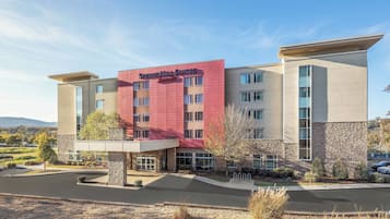 Situated in a landscaped area, this hotel features a modern design with large windows and a stone-textured exterior.