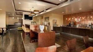 A modern hotel lobby with a bar area, seating, and a television. - Super 8 by Wyndham Cotulla TX (Cotulla)