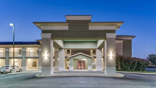 A hotel entrance with a covered walkway, columns, and a car parked in front. - Super 8 by Wyndham Cotulla TX (Cotulla)