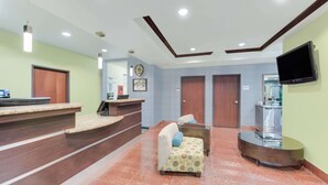 A reception area with a counter, seating, and a TV. - Super 8 by Wyndham Cotulla TX (Cotulla)