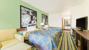 A hotel room with two beds, a TV, a sofa, and artwork on the walls. - Super 8 by Wyndham Cotulla TX (Cotulla)