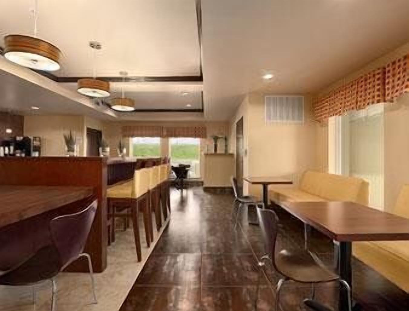 A modern hotel lobby with a reception desk, seating area, and a view of the outdoors.