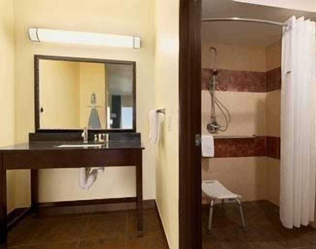 A bathroom with a sink, mirror, and shower.