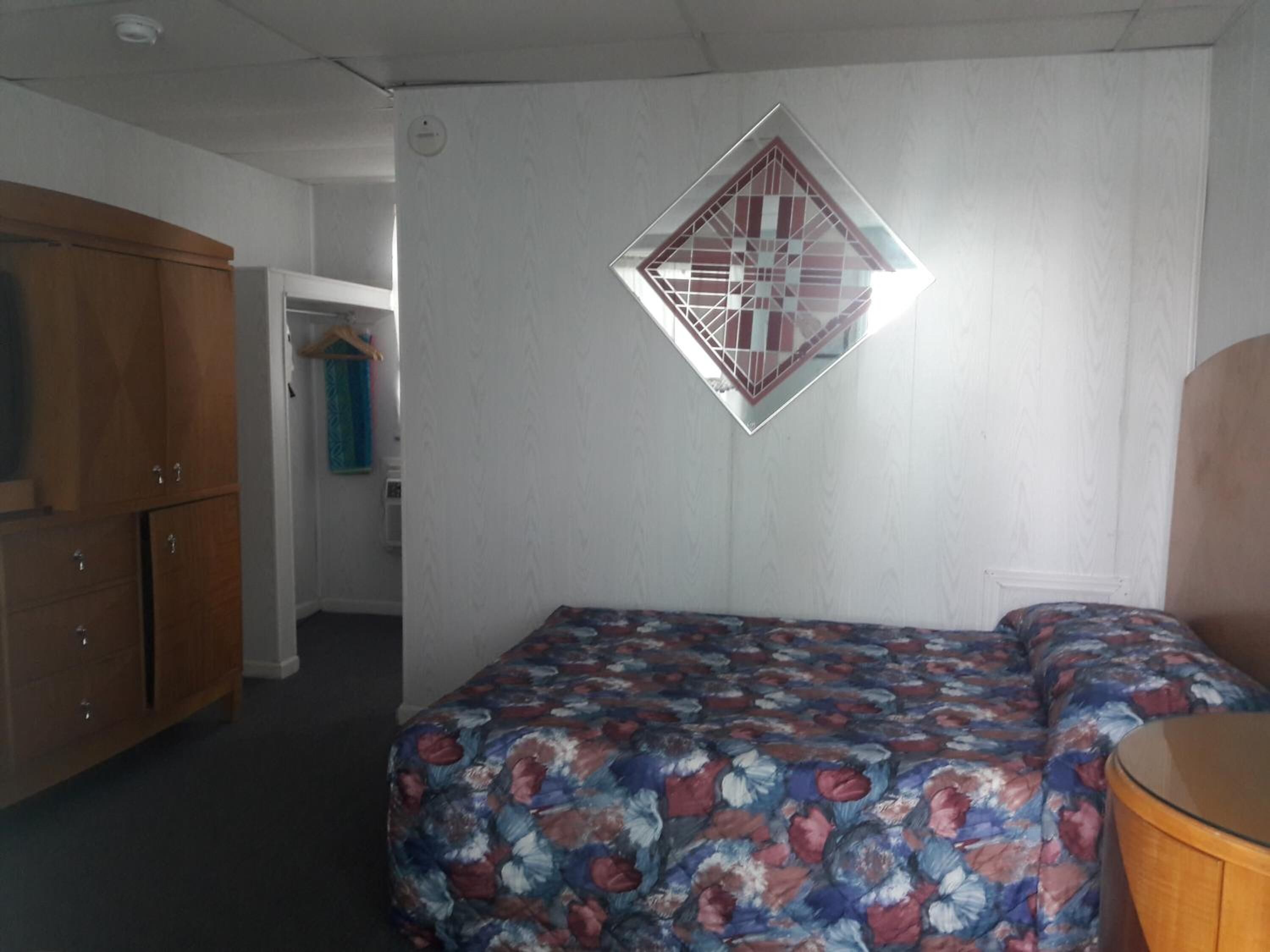 A bedroom with a bed, a wardrobe, and a wall-mounted decorative item.