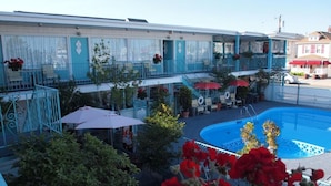 Un hotel con piscina, zona de estar exterior y un área cubierta con sombrillas.