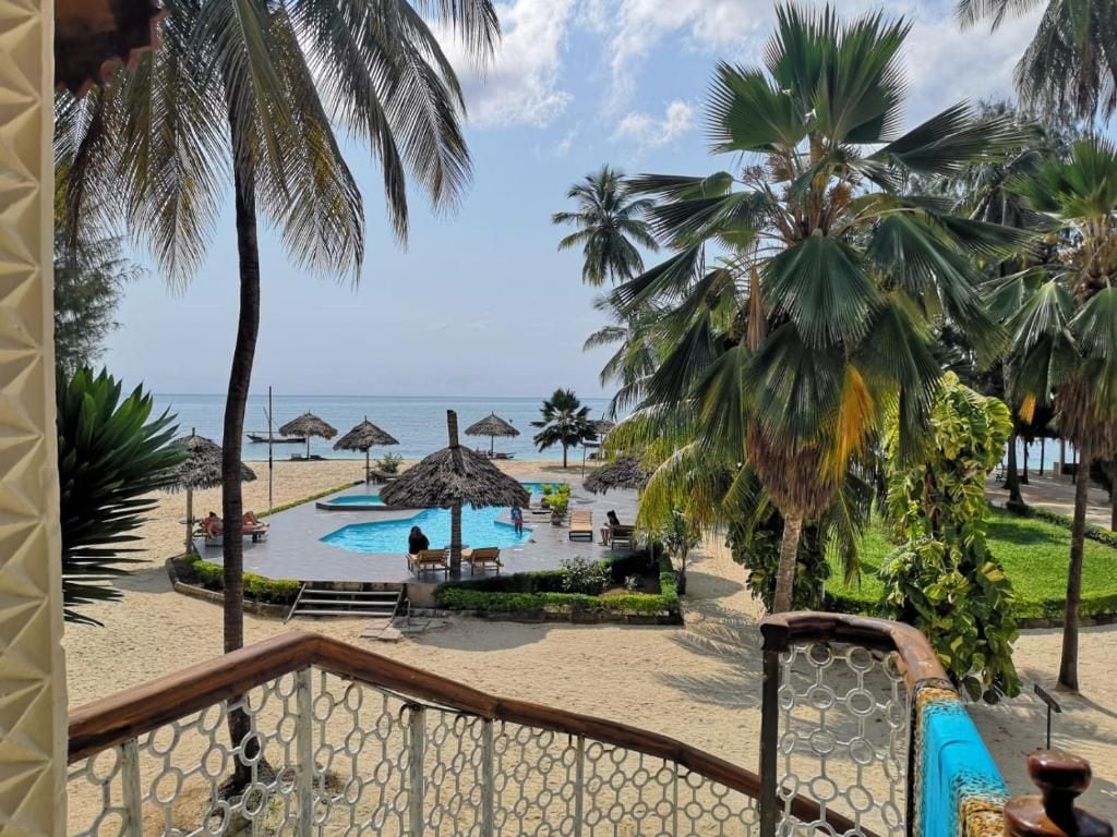 Ein Strandresort mit Poolbereich, Palmen und Blick auf das Meer.
