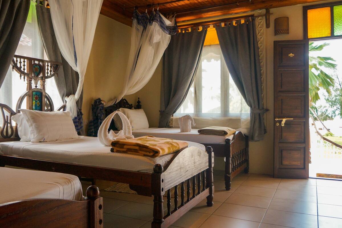 A traditional room with a bed, a chair, and a window with curtains.