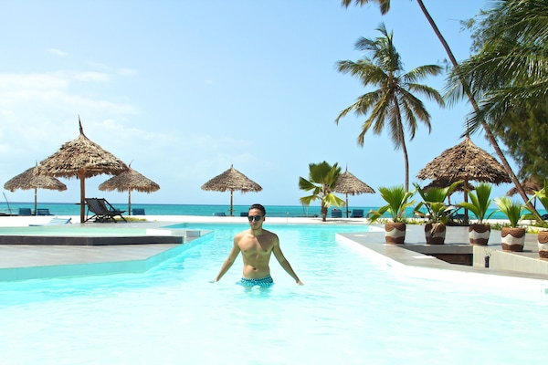 Una piscina al aire libre, sombrillas, sillones reclinables de piscina