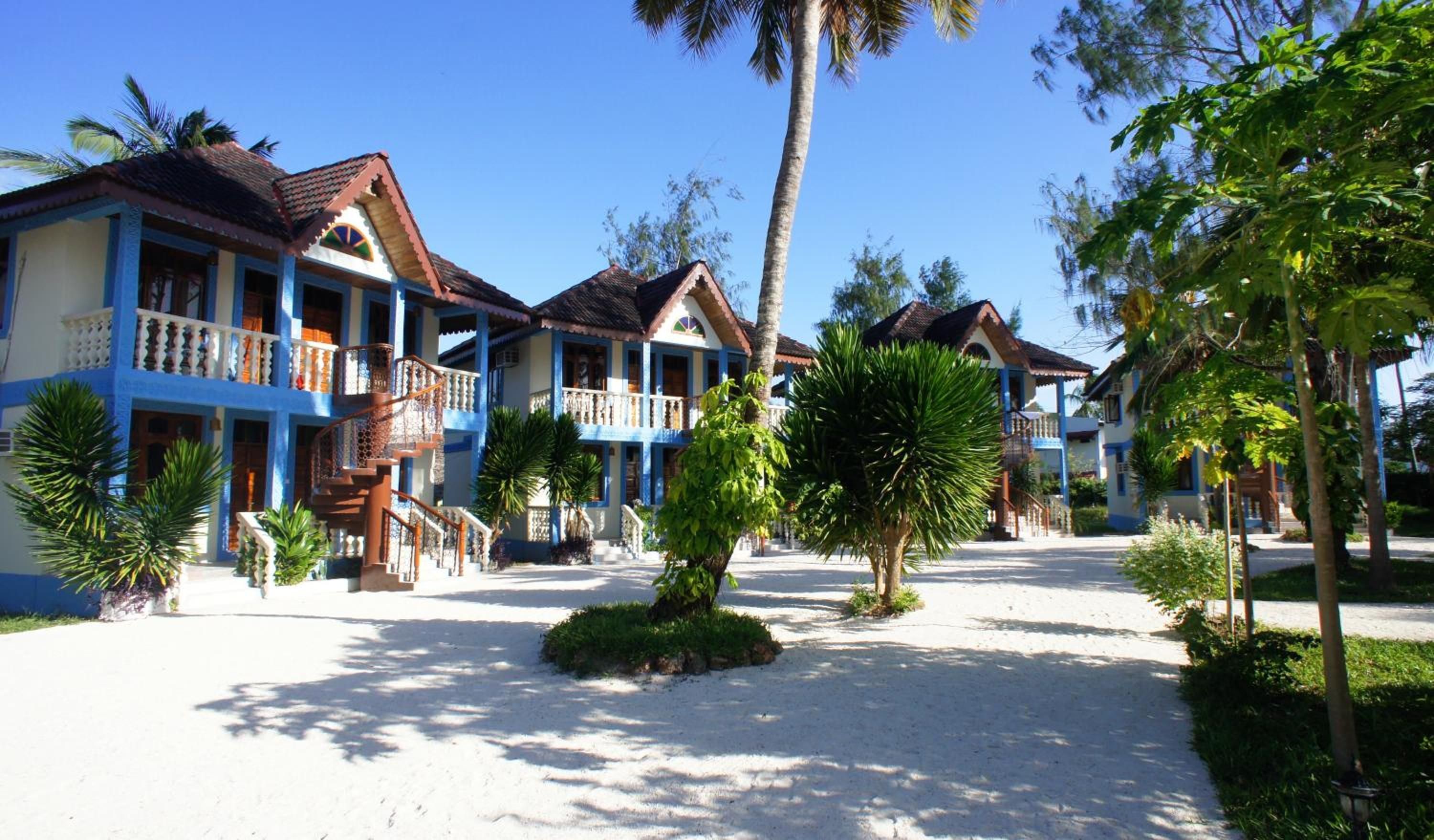 Un resort con varias edificaciones de dos pisos, cada una con un balcón y una escalera que conduce a la entrada.