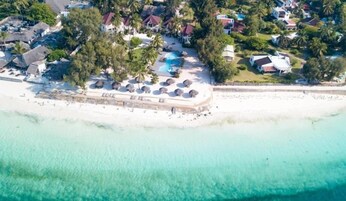 An aerial view of a coastal resort with a beach, swimming pool, and multiple villas.