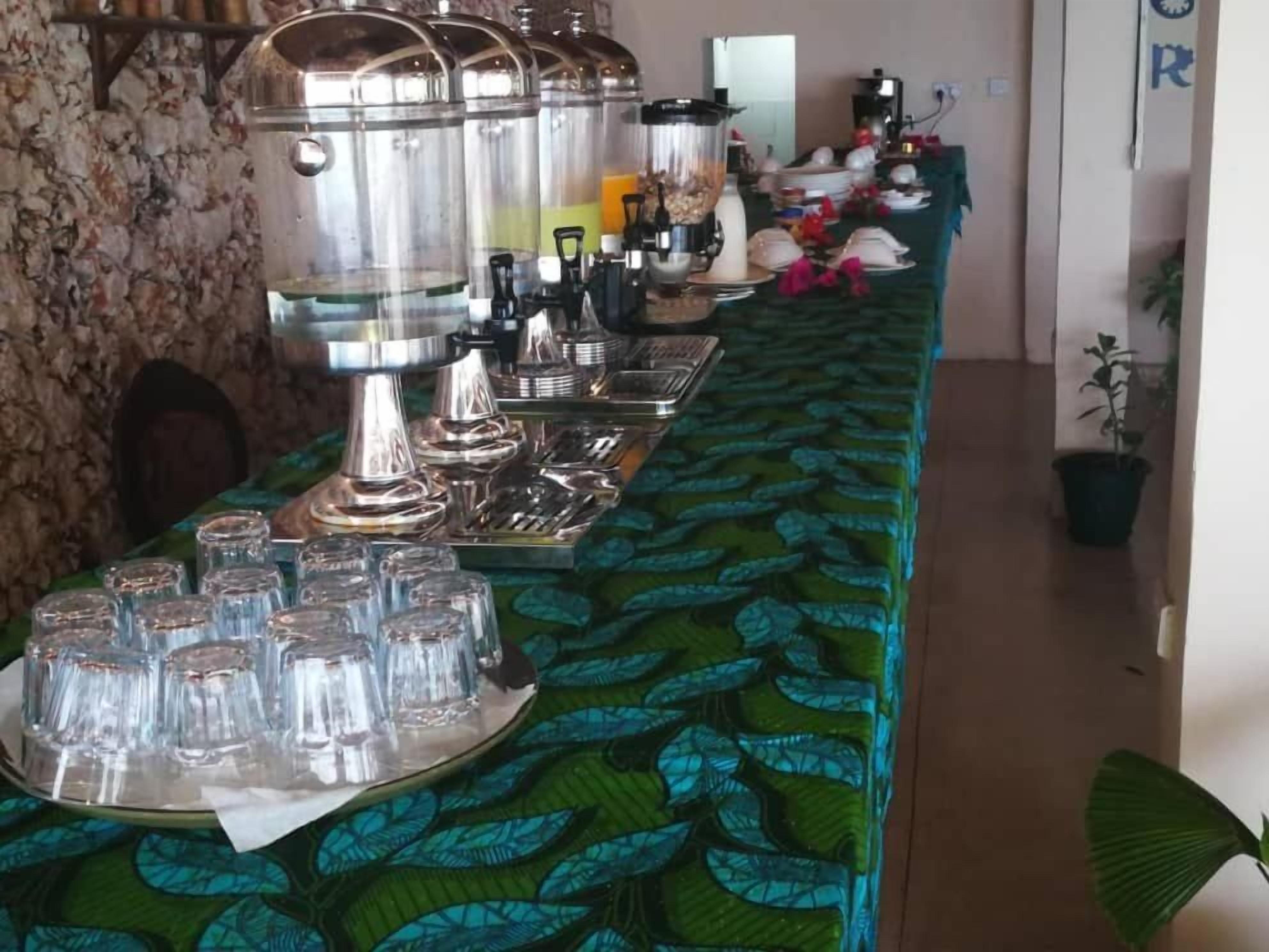 A buffet setup with multiple serving stations, including a beverage dispenser and a variety of food containers.